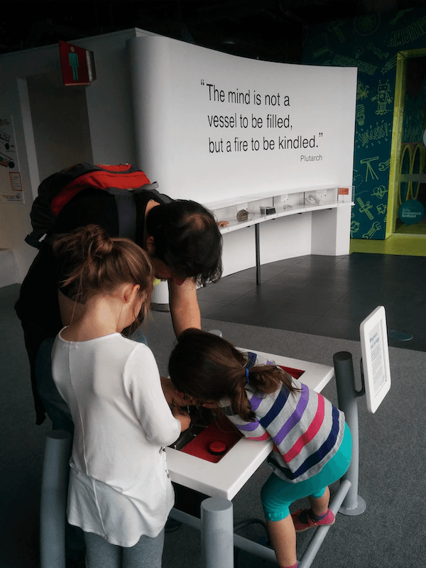 My husband and two children. They are leaning over a table at an exhibit at the Glasgow Science Museum.